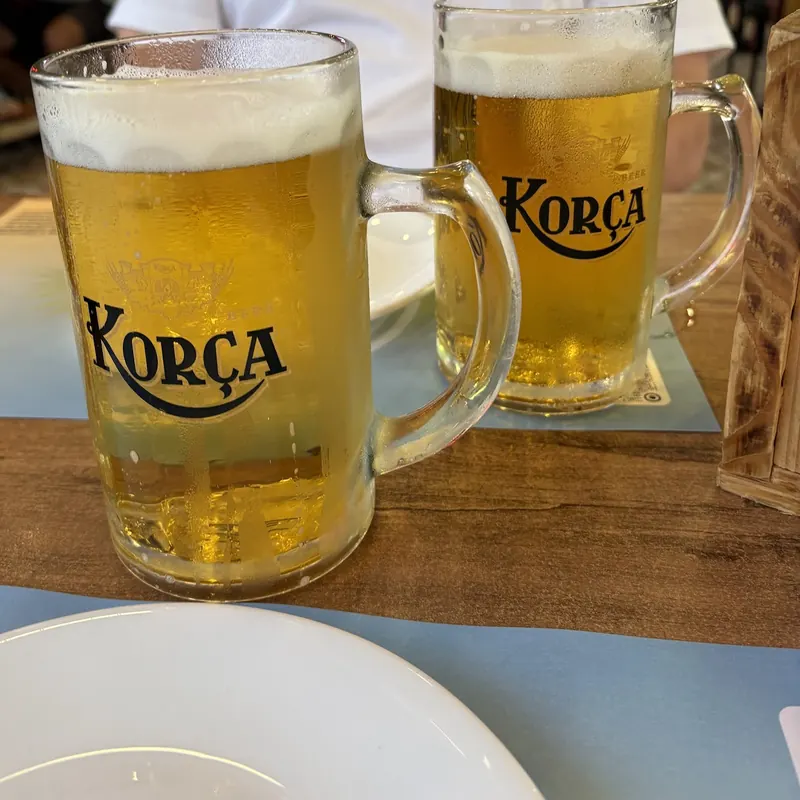 Two mugs of Korça beer on a wooden table