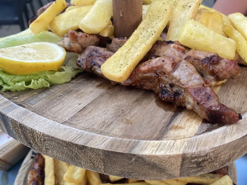 Grilled meats with lemon and fries on a two-tier wooden board