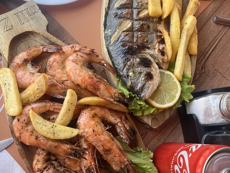 Grilled prawns and a whole grilled fish with fries and lemon