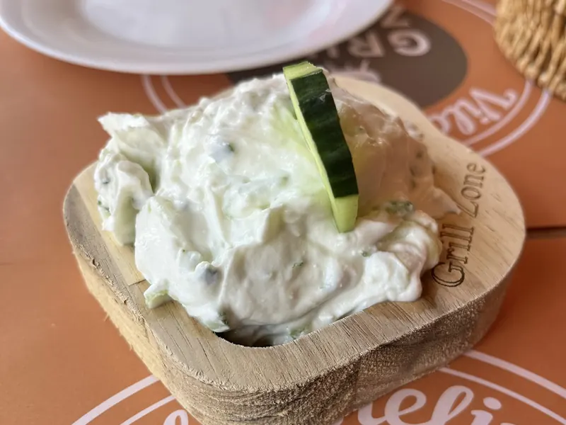Homemade tzatziki with a slice of cucumber in a wooden bowl